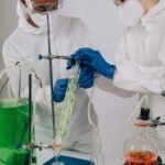 Two scientists in protective gear conducting an experiment in a laboratory setting.