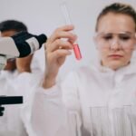 Researchers conducting experiments in a laboratory setting using microscopes and test tubes.