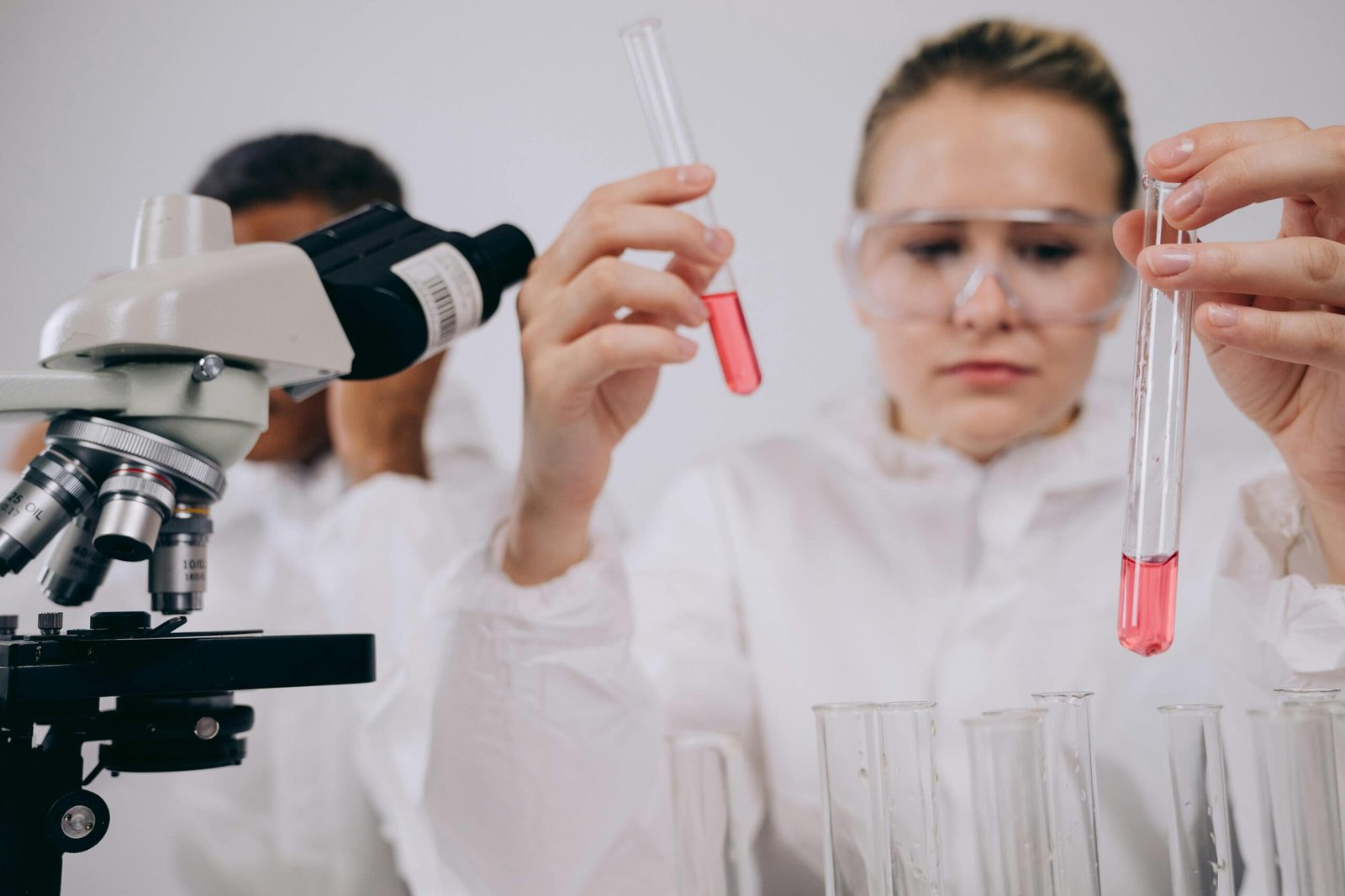 Researchers conducting experiments in a laboratory setting using microscopes and test tubes.